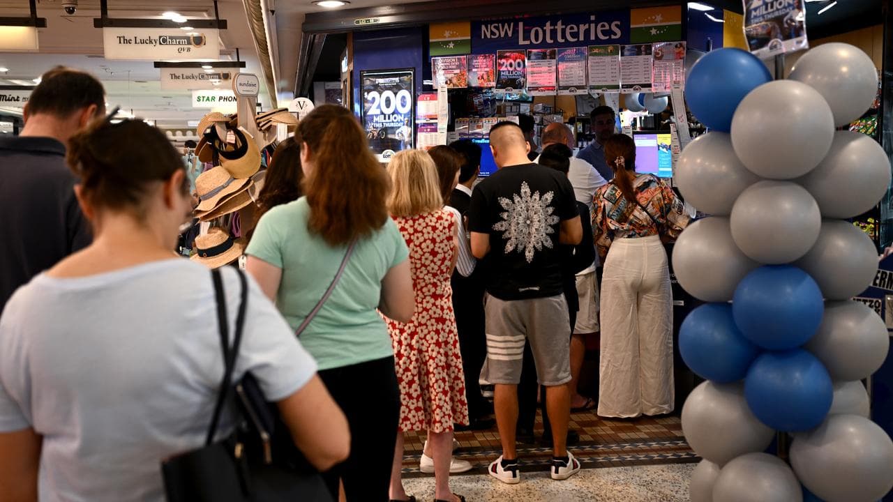 Peope are seen queueing at a newsagent to buy Powerball tickets