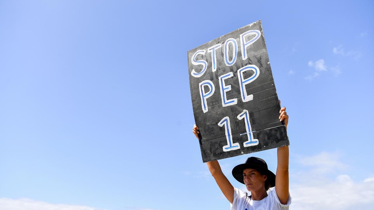 Woman holds placard aloft saying STOP PEP 11