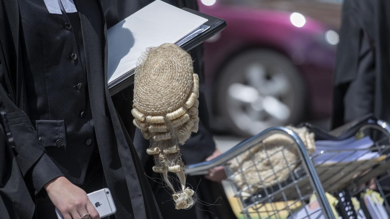 A barrister carries documents and a wig at the Supreme Court