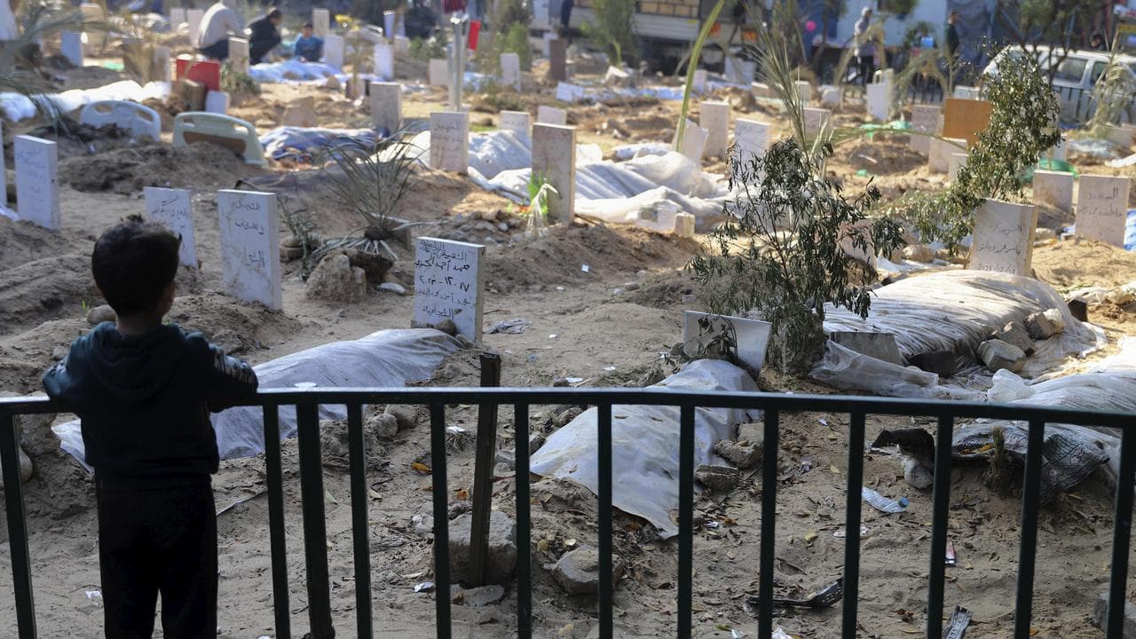 A Palestinian child looks at a makeshift cemetery inside Shifa grounds