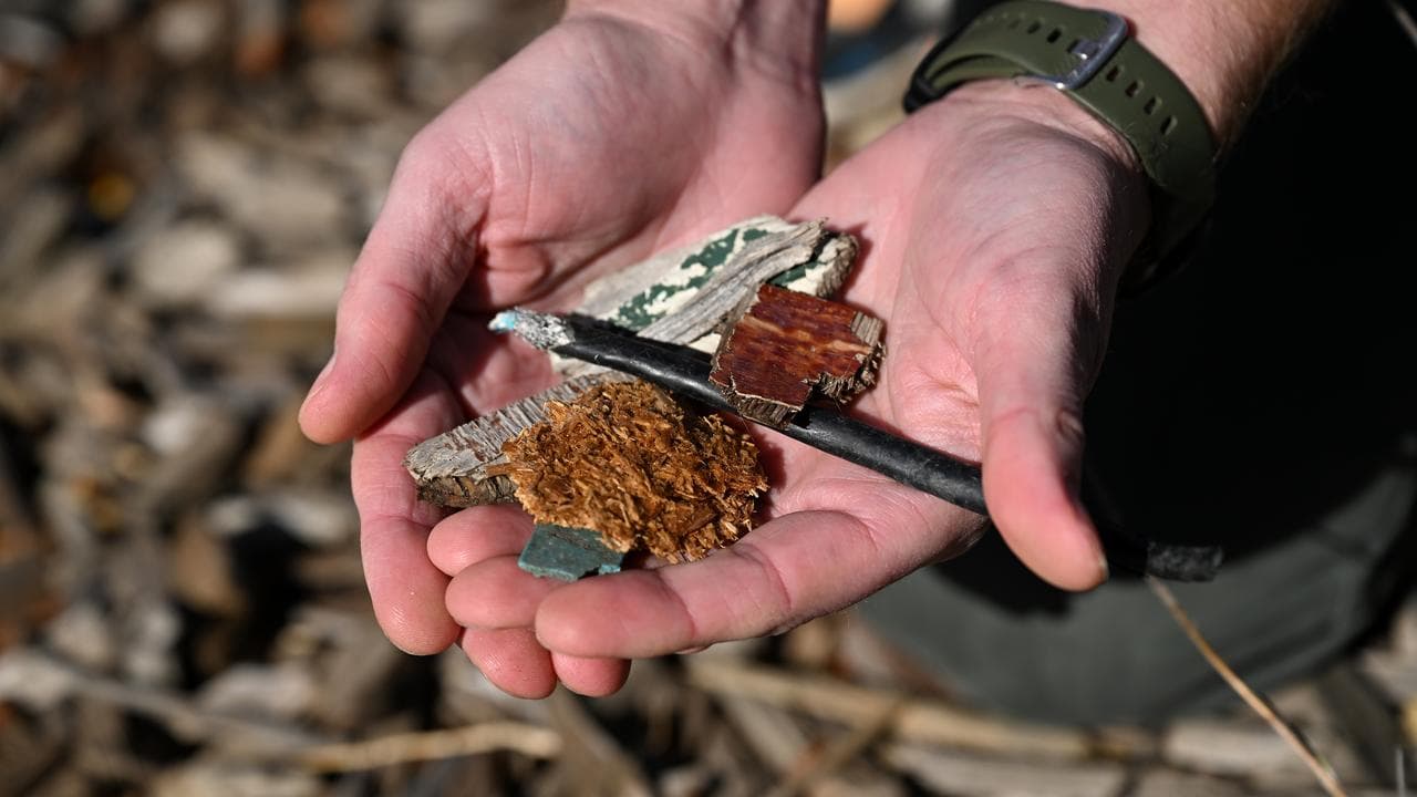Local resident holds items found in mulch next to a closed playground