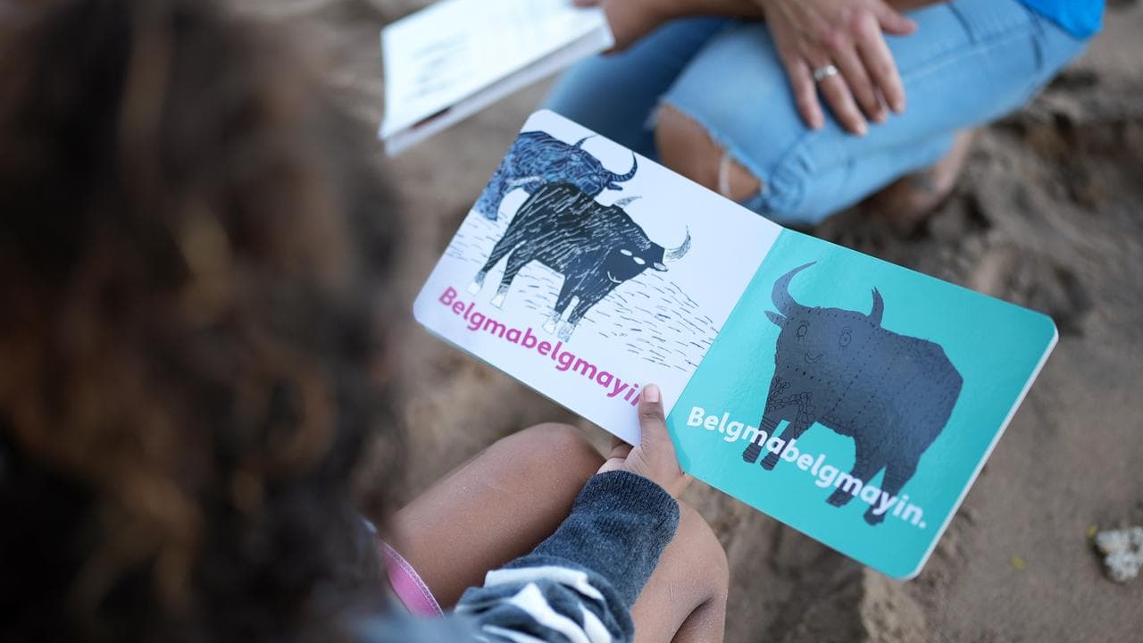 A child reads a book in an Indigenous language.