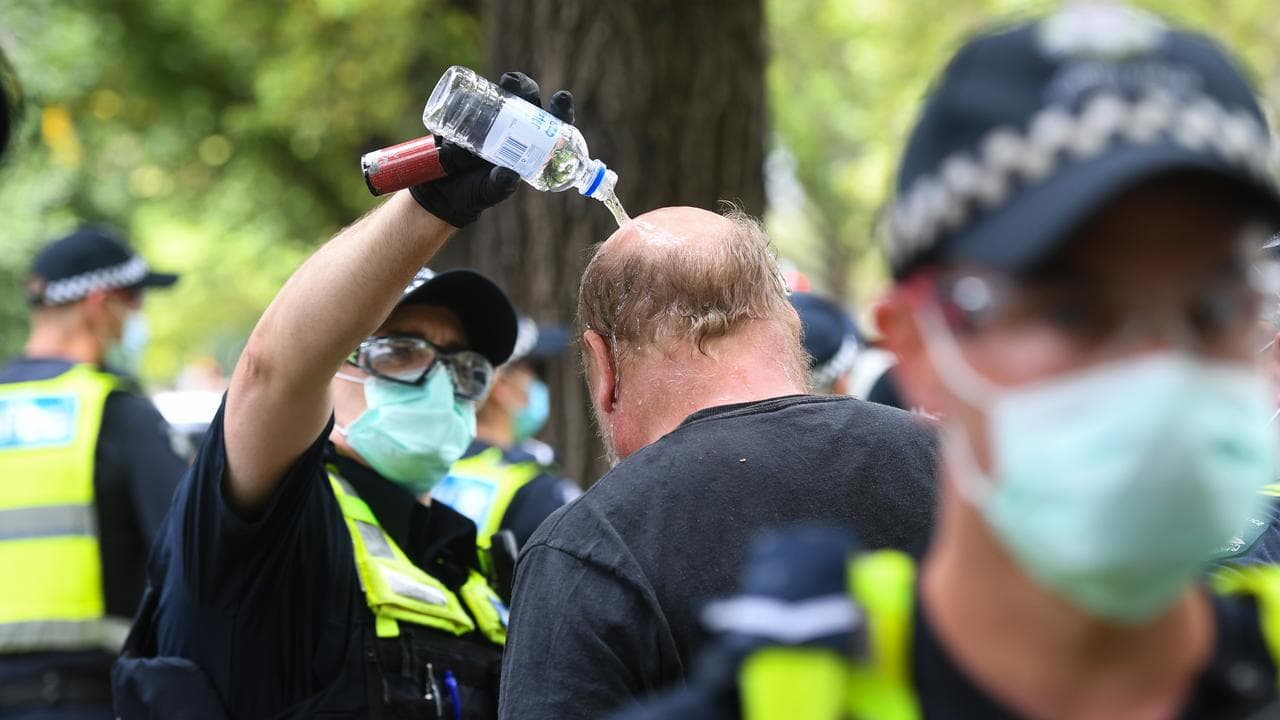 Police pour water on a pepper-sprayed protester.