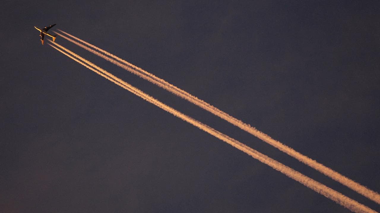 A plane in the evening sky with condensation trails