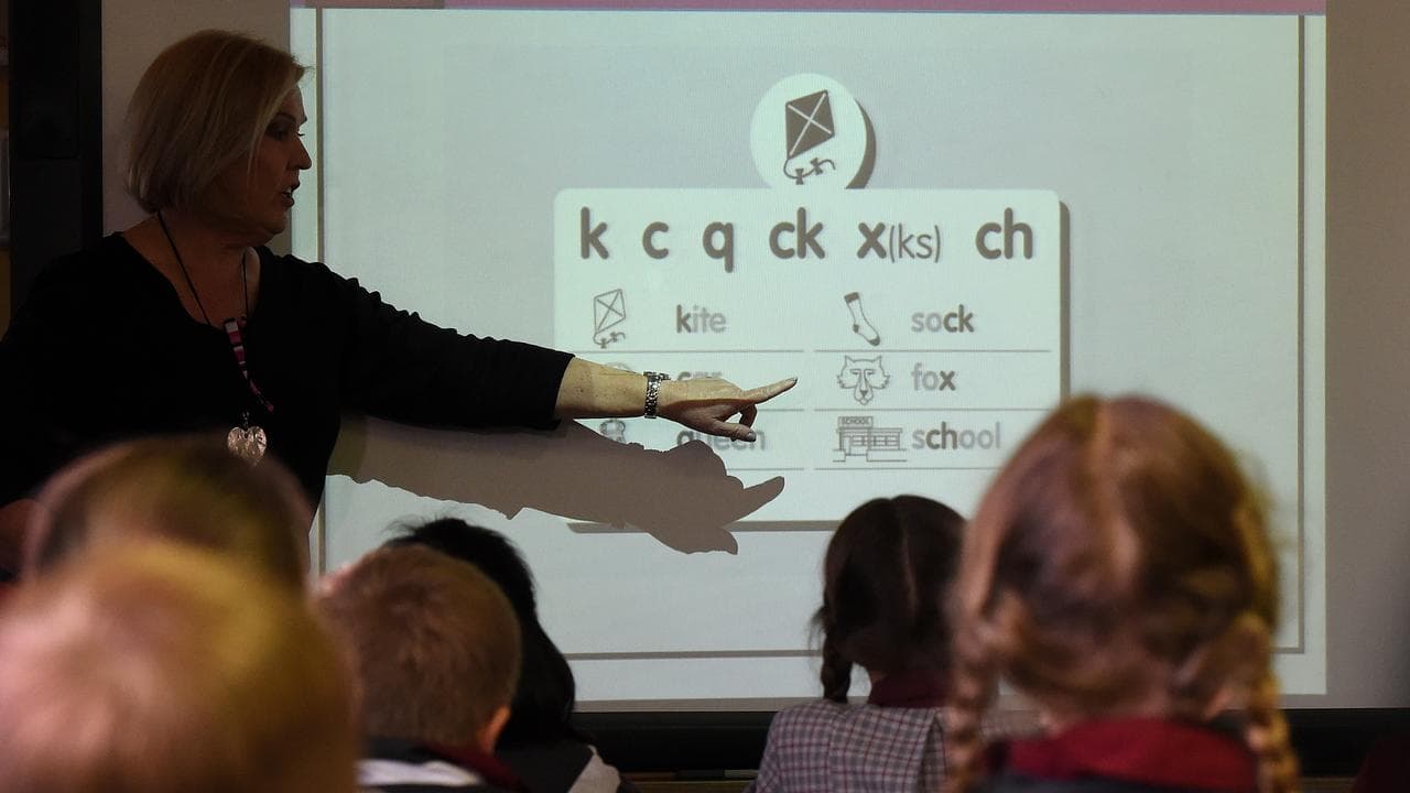A teacher points at a board