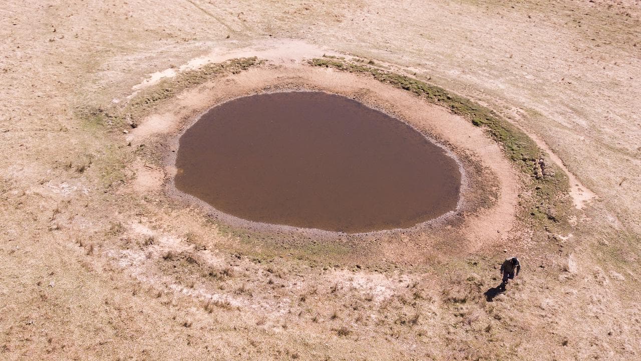Farmer James Clarke checking the water level at one of his dams