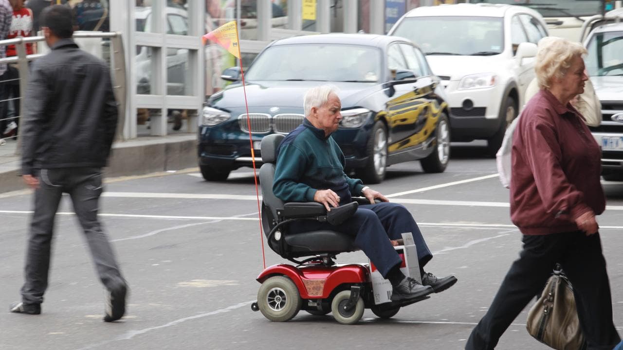 A man rides on his electric wheelchair in the CBD of Melbourne