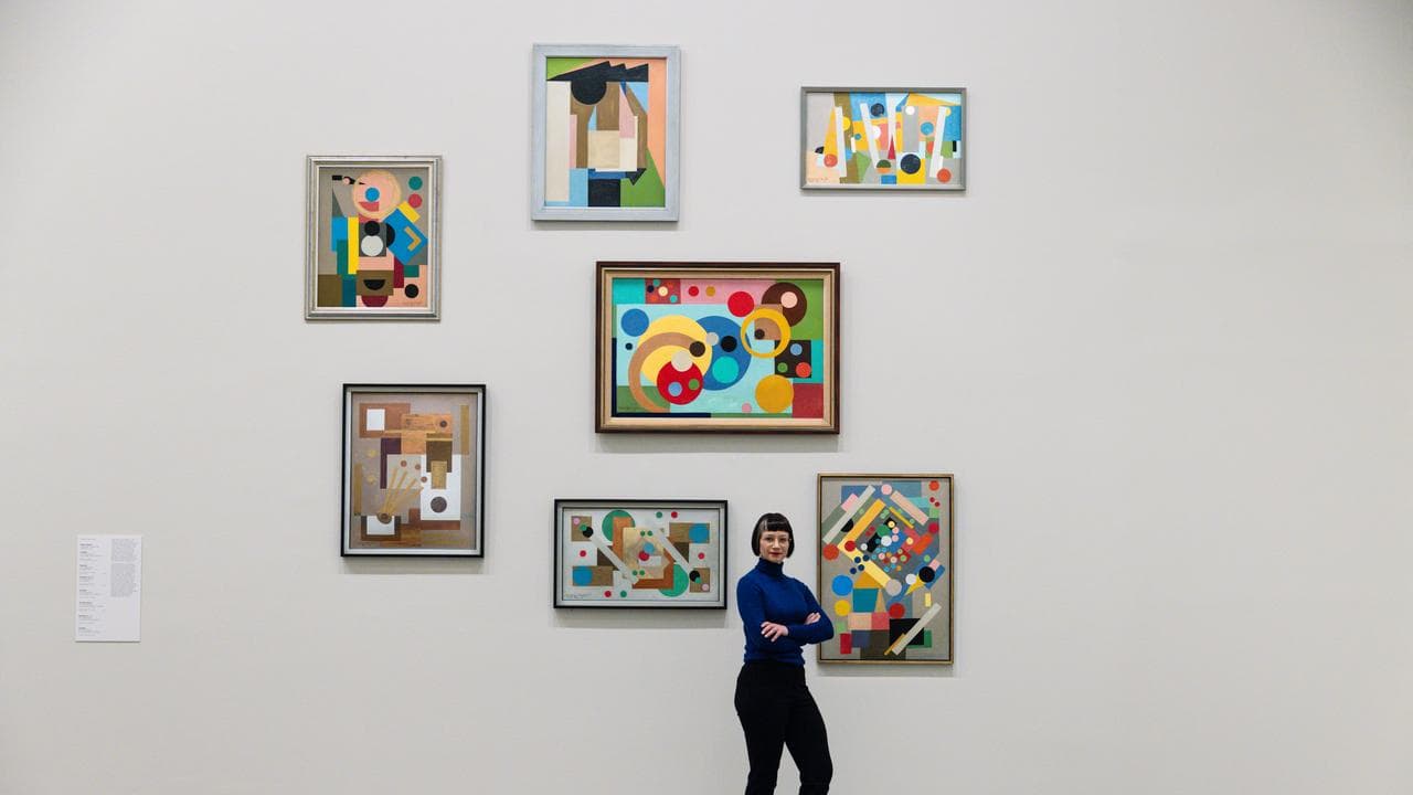 Curator Beckett Rozentals with Ralph Balson artworks at the NGV