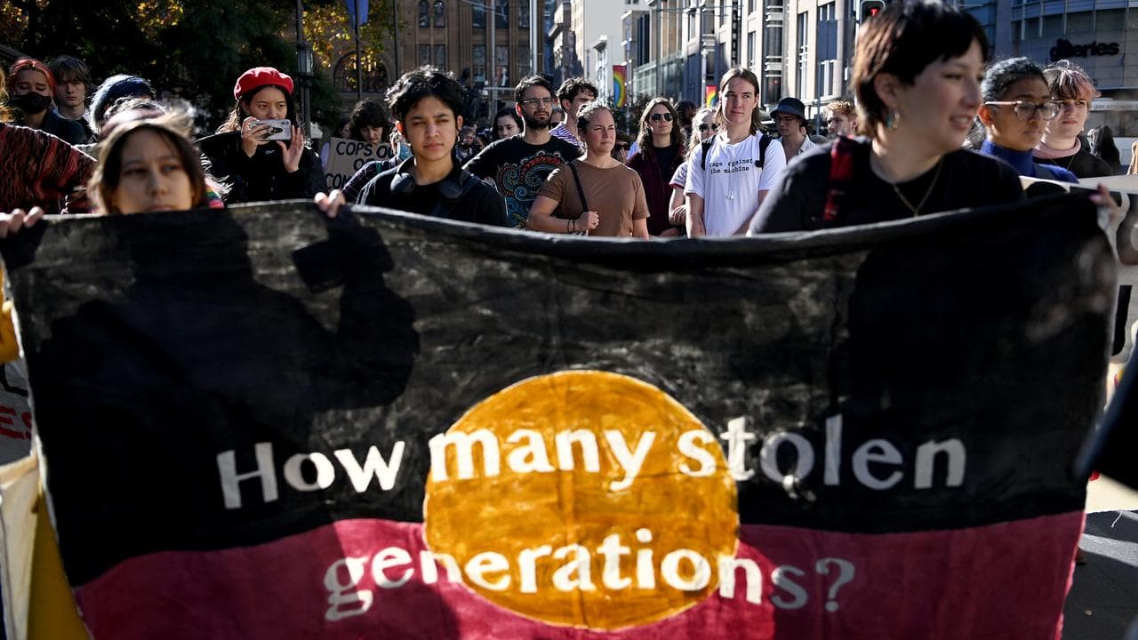 Marchers carry a 'Stop The Stolen Generation!' sign at a march.