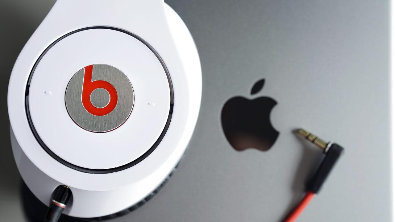 Beats headphone against an Apple logo.
