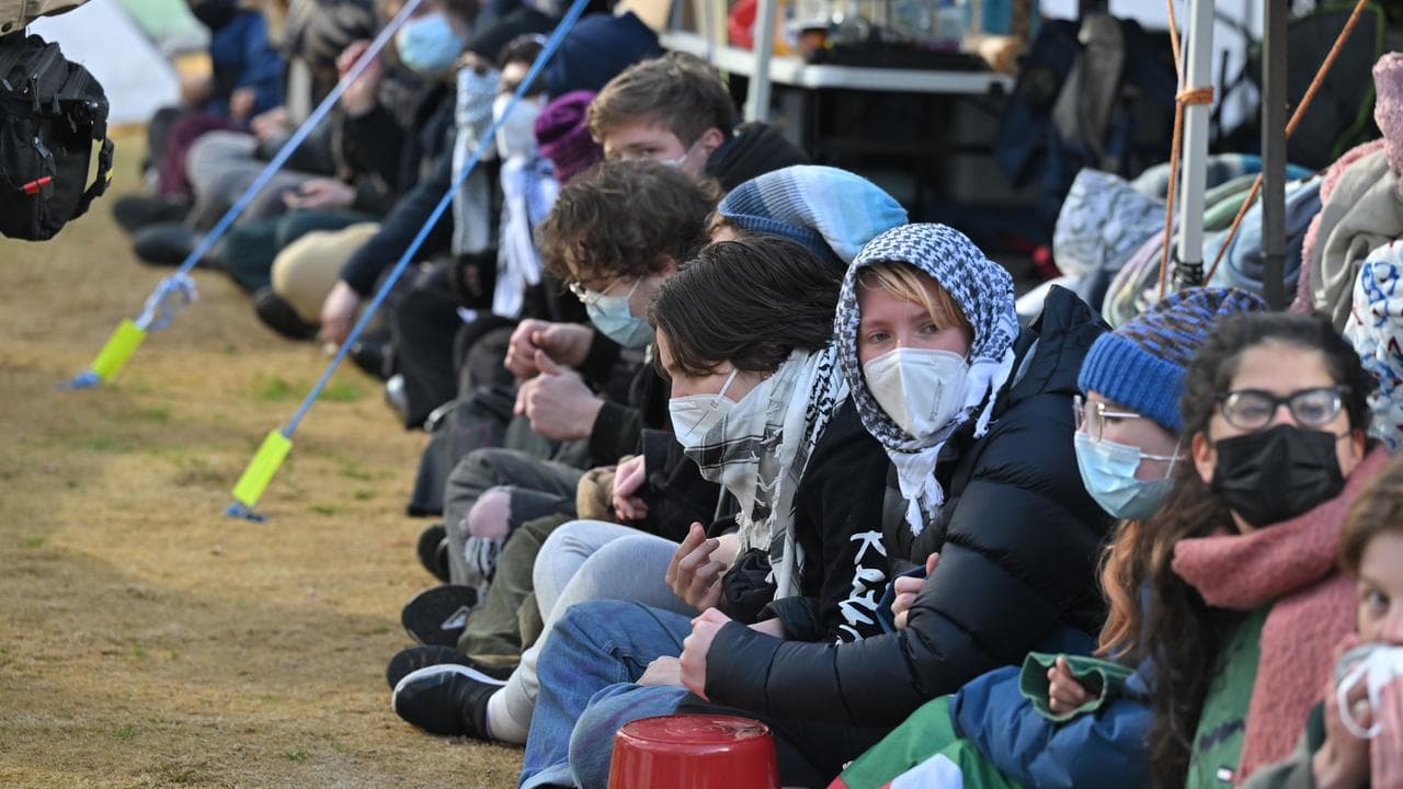 Protesters sit in a line with arms linked.