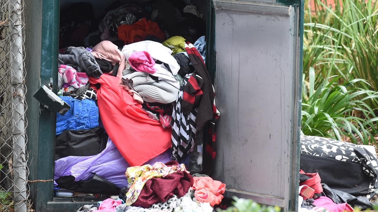 An overflowing clothing recycling bin.