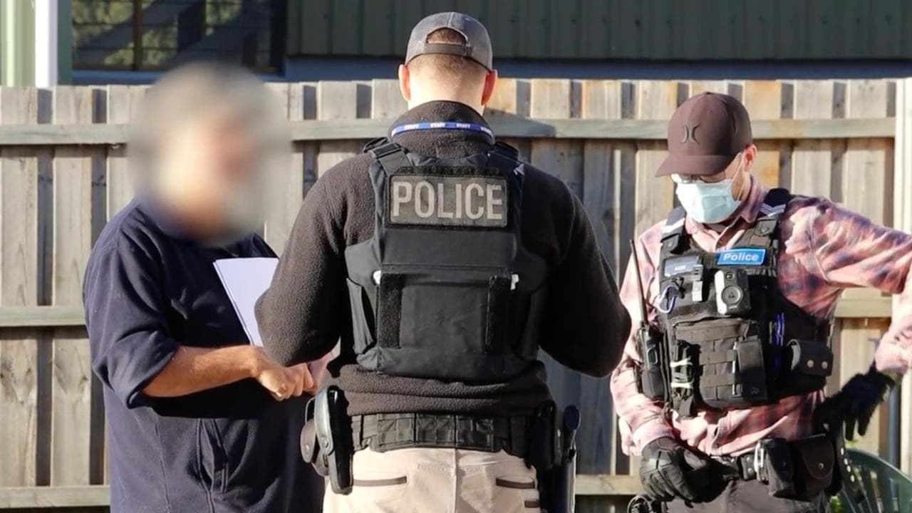 Police with a person during a raid.