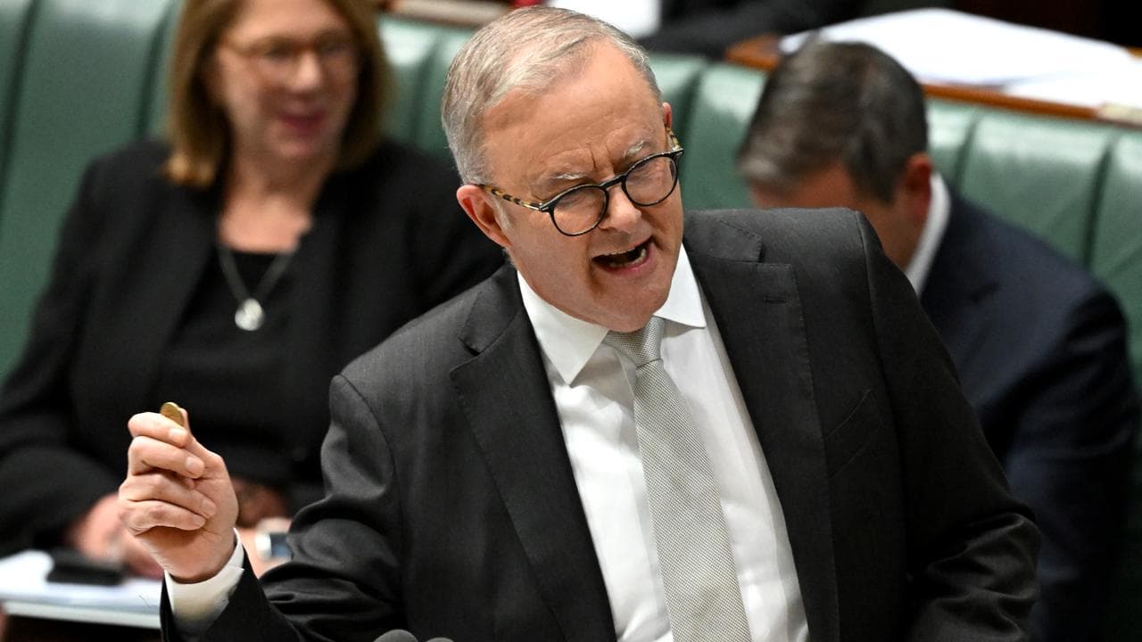 Prime Minister Anthony Albanese holds up a One Dollar coin