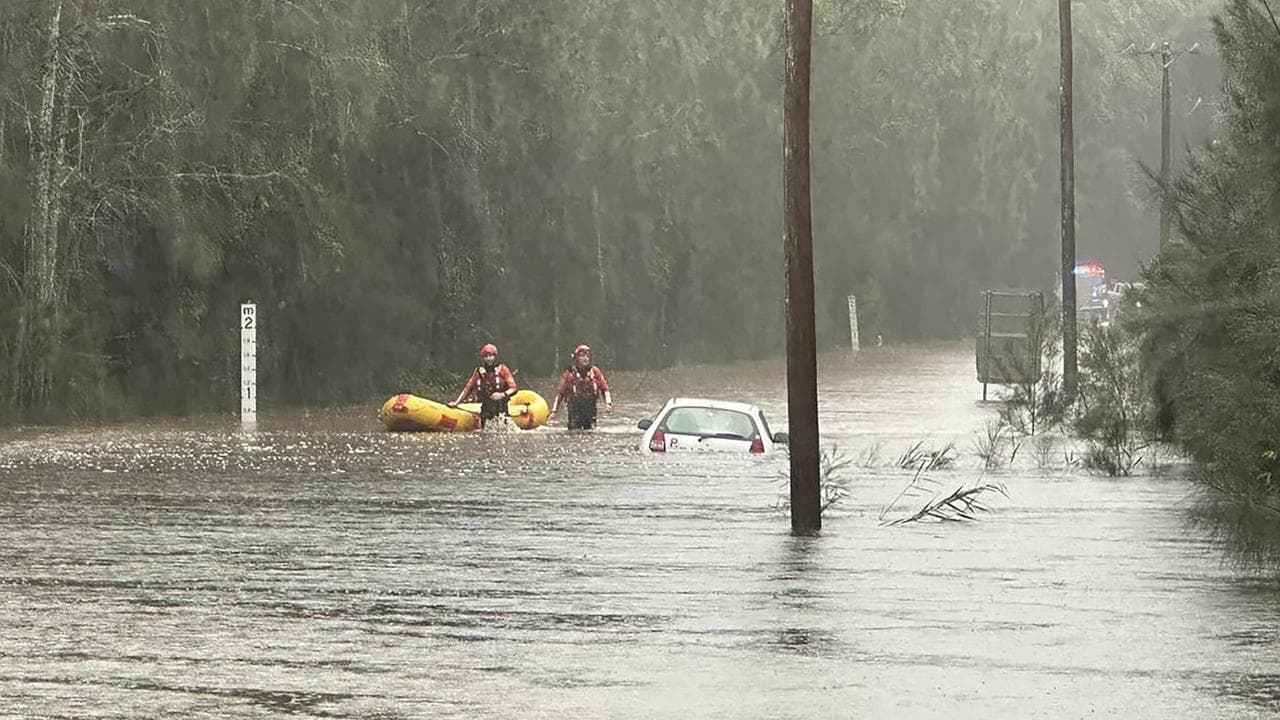 A rescue crew checks out a submerged car after heavy rains.