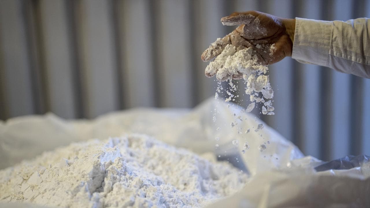 A worker stirs powdered lithium with his hand at SQM processing plant