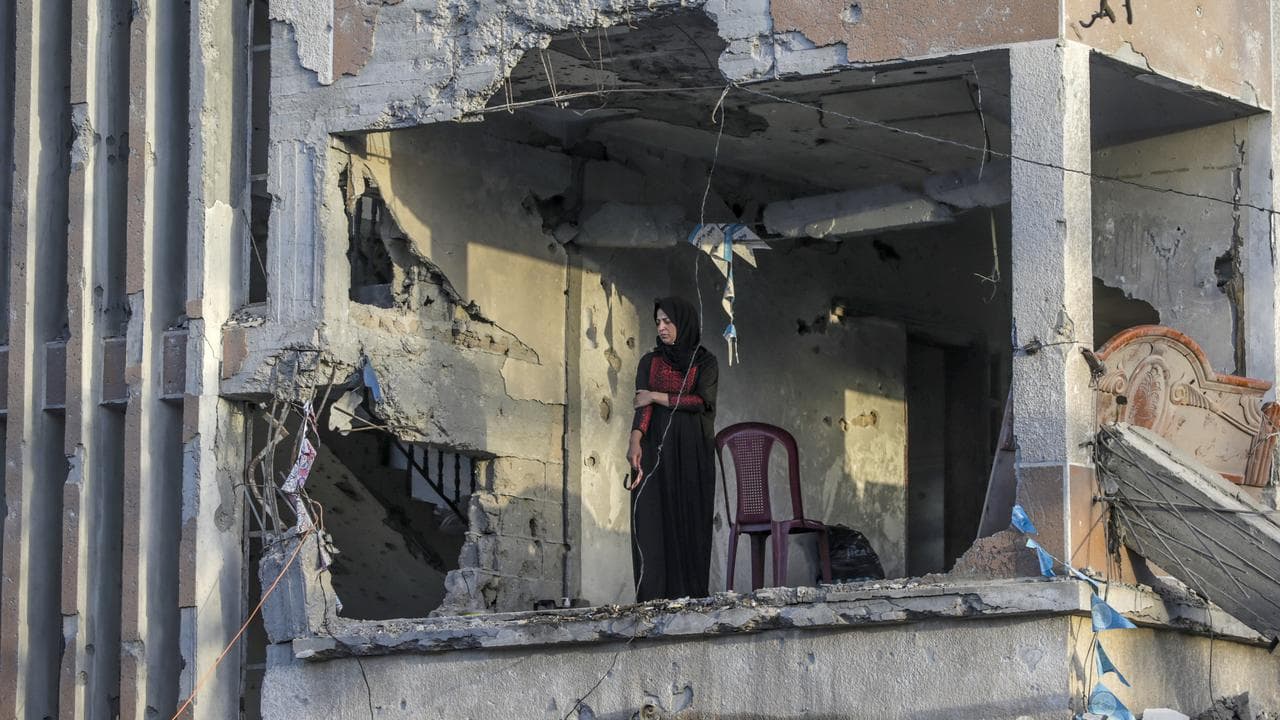 Palestinian woman looks from her destroyed house in Khan Younis