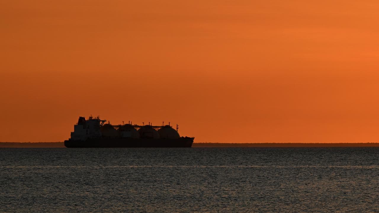 An LNG carrier ship sails out of Darwin Harbour as the sun sets.
