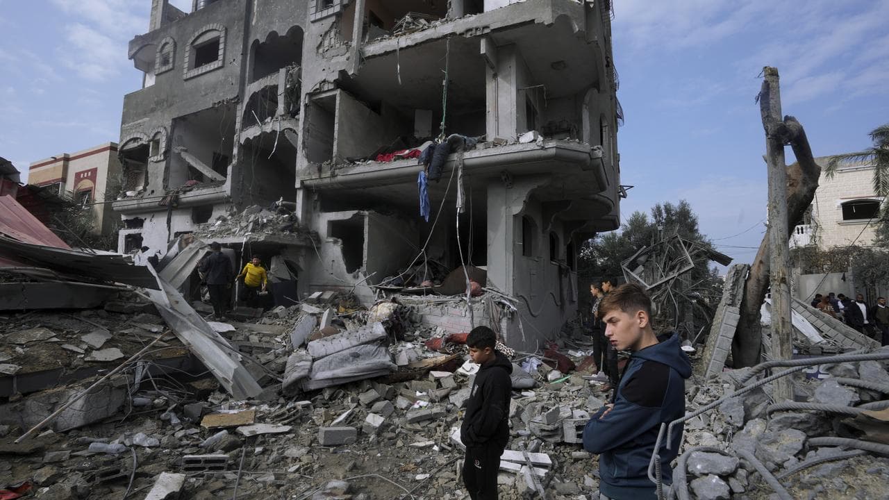 People stand outside a building destroyed by bombings.