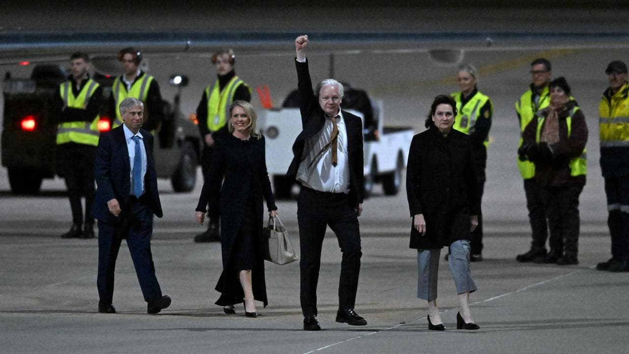 Julian Assange waves at supporters after arriving at Canberra Airport