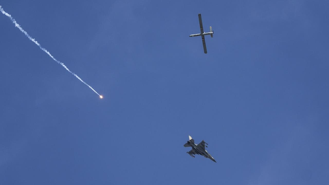An Israeli fighter jet releases flares, and a drone is seen from Rafah