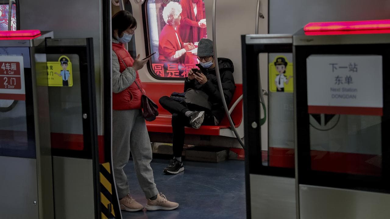 A picture of two commuters on a train in Beijing.