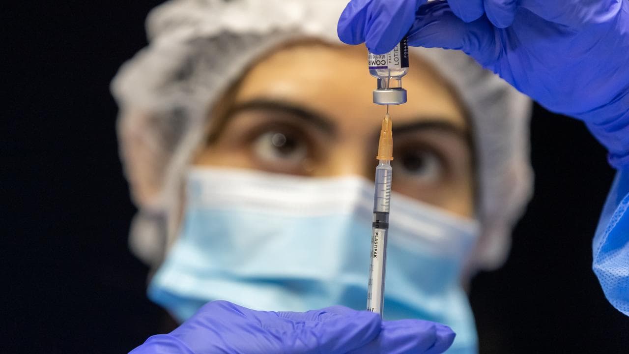 health care worker fills a syringe with Pfizer vaccine