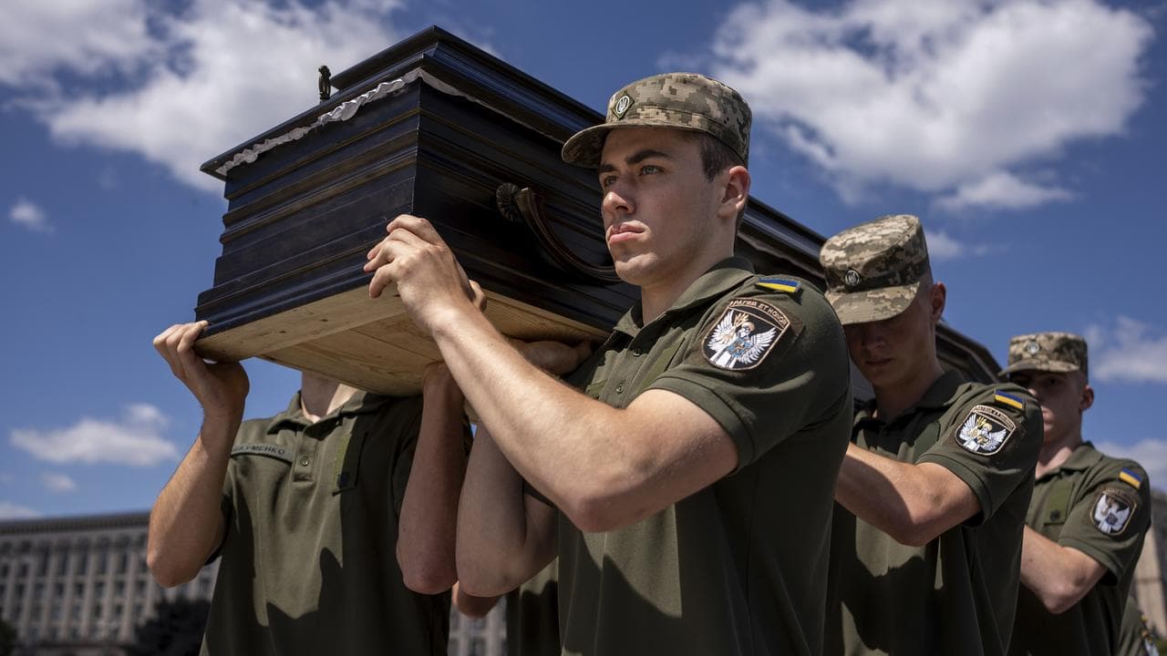 Ukrainian servicemen carry a coffin of British combat medic