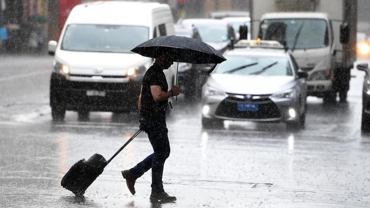 A pedestrian crosses the road carrying an umbrella in Sydney.
