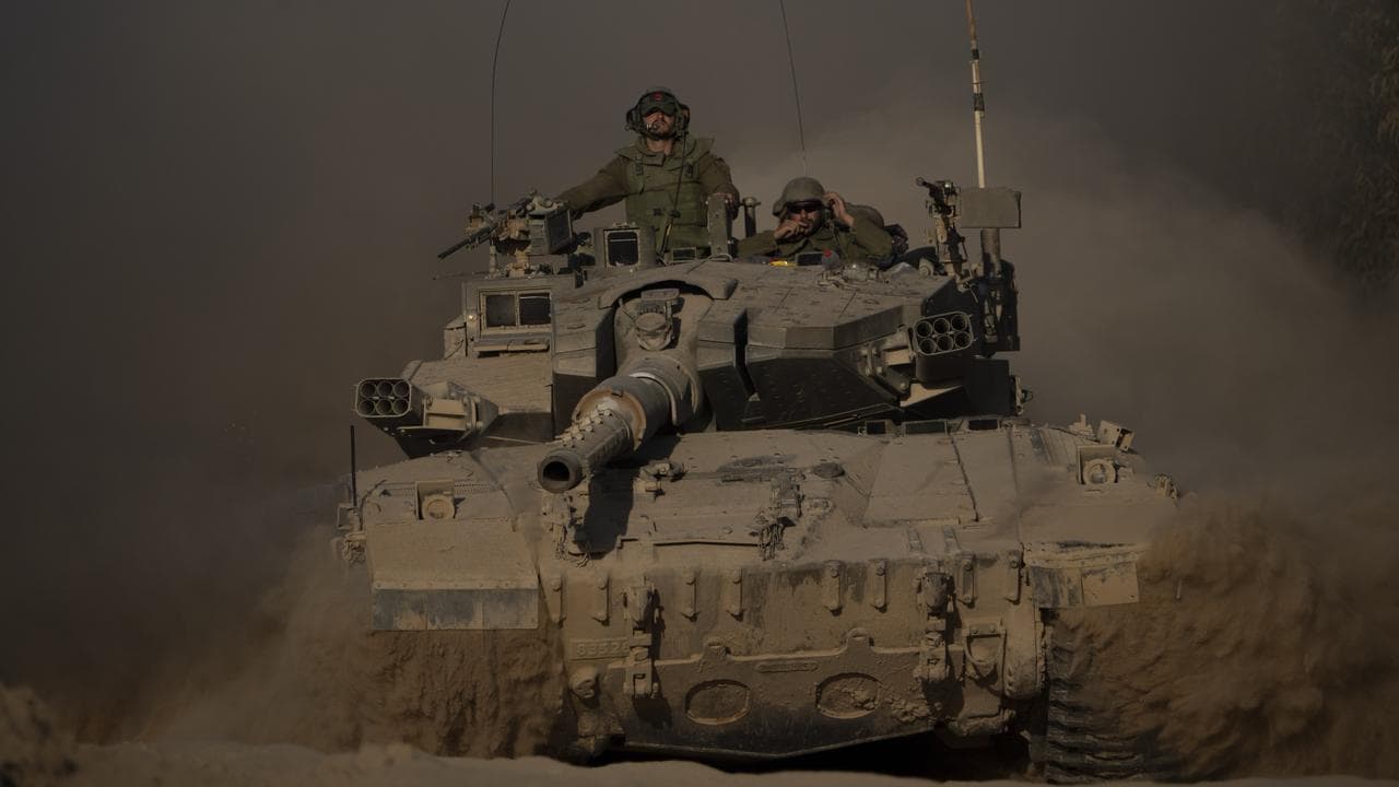 Israeli soldiers move on the top of a tank near the Gaza border