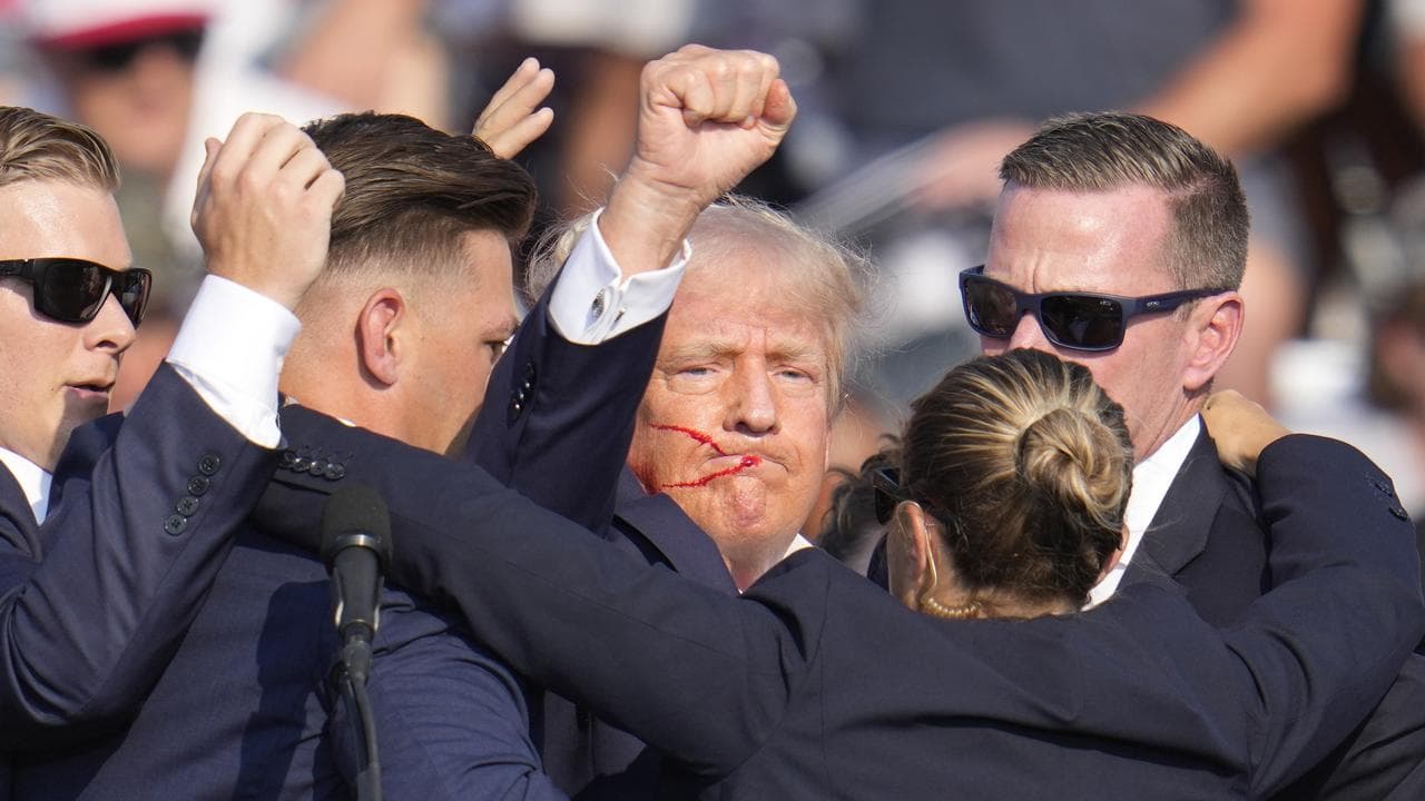 Donald Trump punches the air after taking a bullet across the ear.