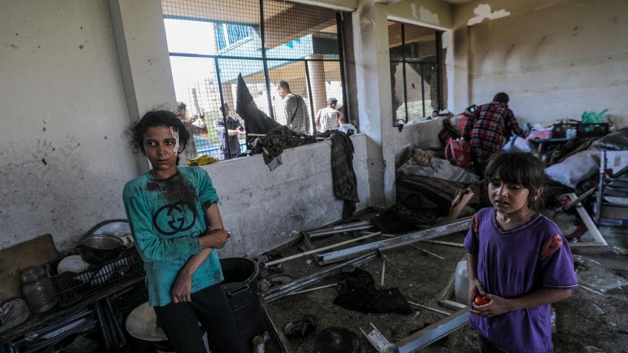 An injured Palestinian girl stands among debris