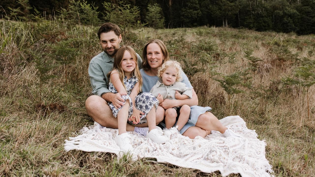 A family sit on a picnic rug.