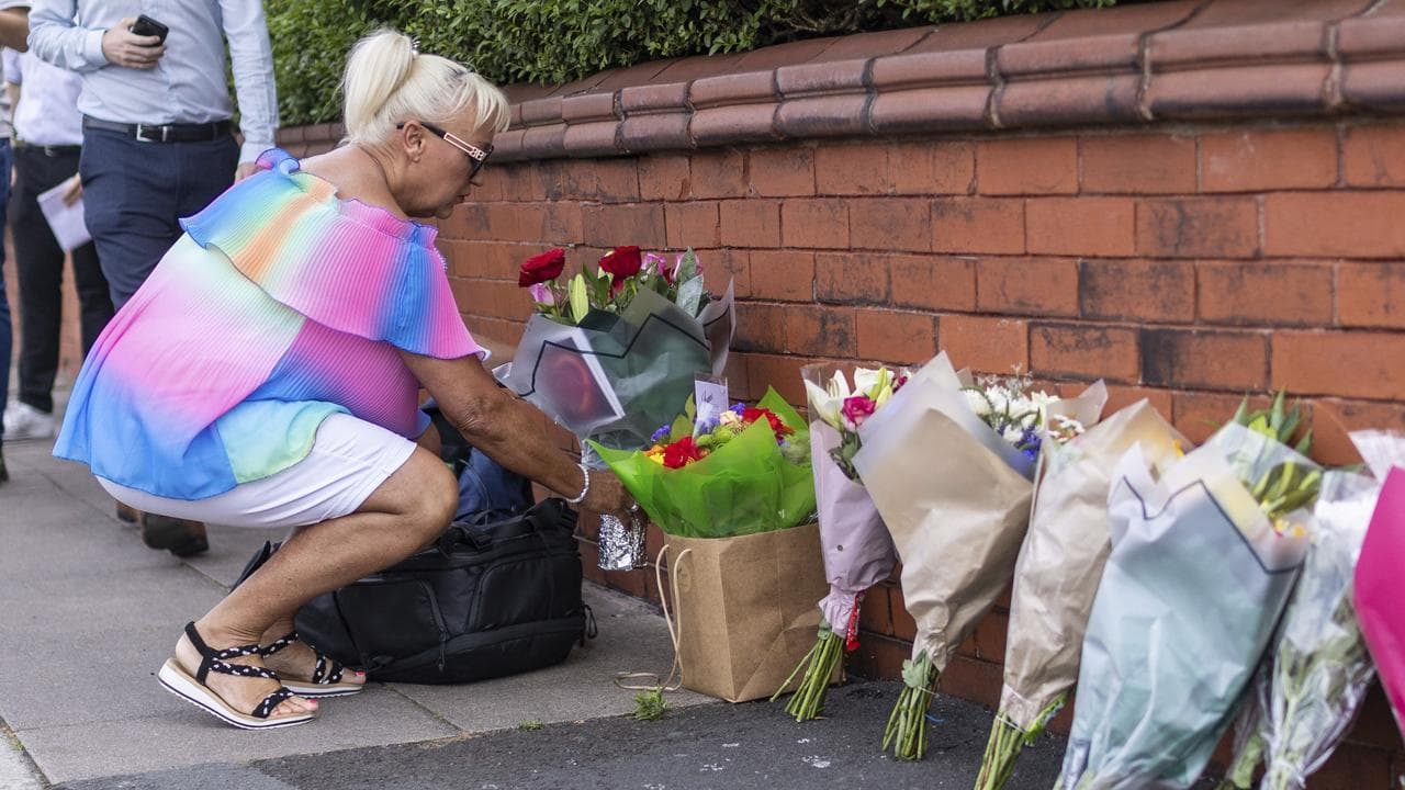 A woman leaves flowers near the scene in Hart Street, Southport