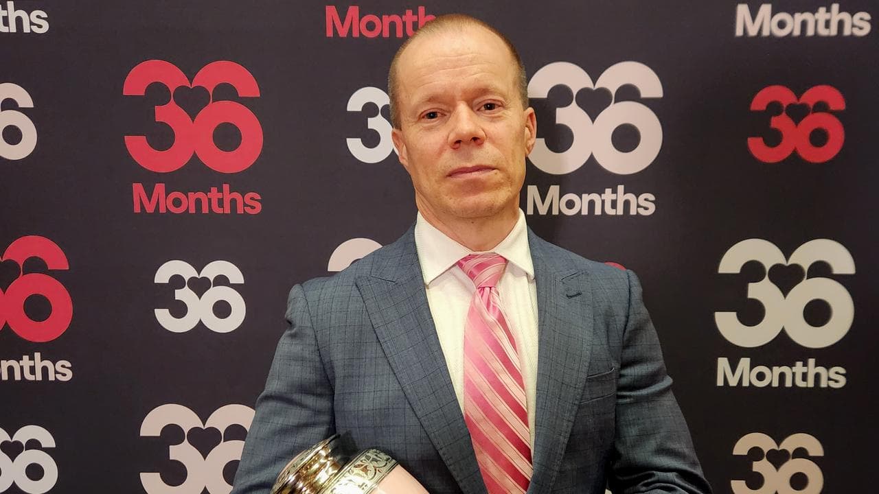 Man holds daughter's urn in front of wall saying '36 months' 