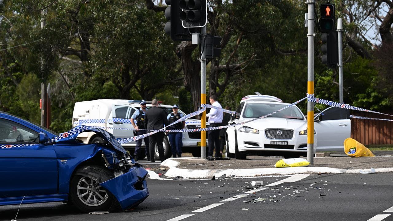 Two cars sit damaged on a street.