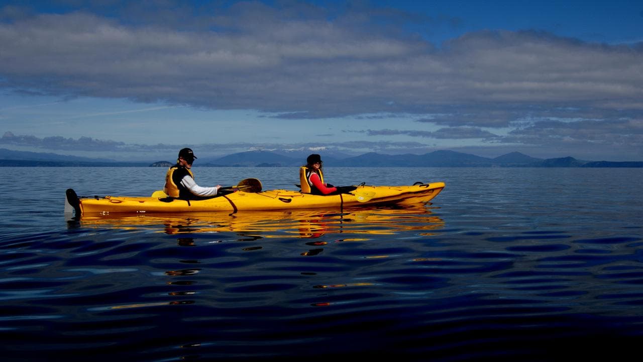 Visitors kayak on Lake Taupo in the North Island of New Zealand.