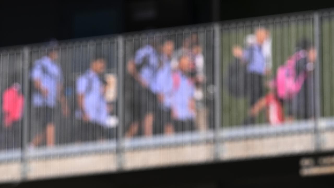 Students walk behind an opaque plastic wall. 