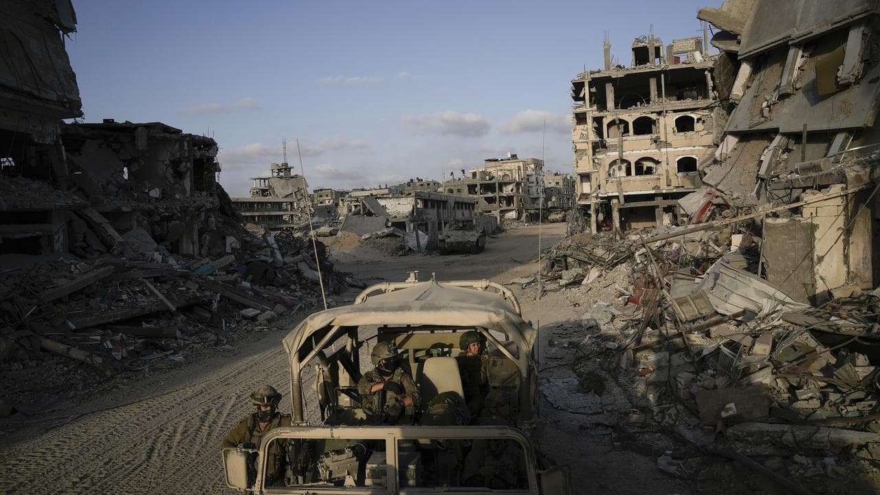 Israeli soldiers move next to destroyed buildings in Gaza