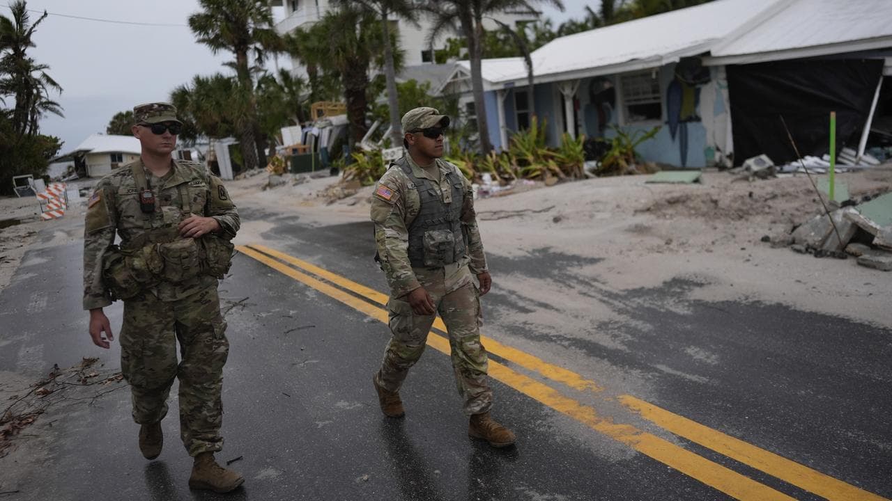 Florida Army National Guard members walk past damage from Helene