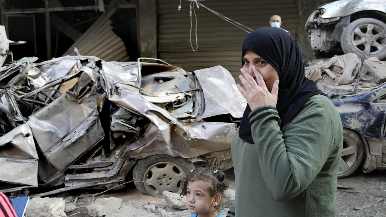 A woman passes in front of destroyed cars in Beirut