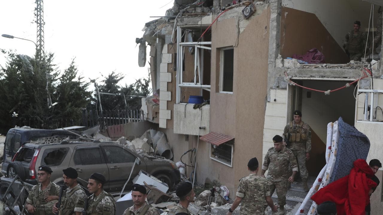 A man carries mattresses from a destroyed building hit by Israel