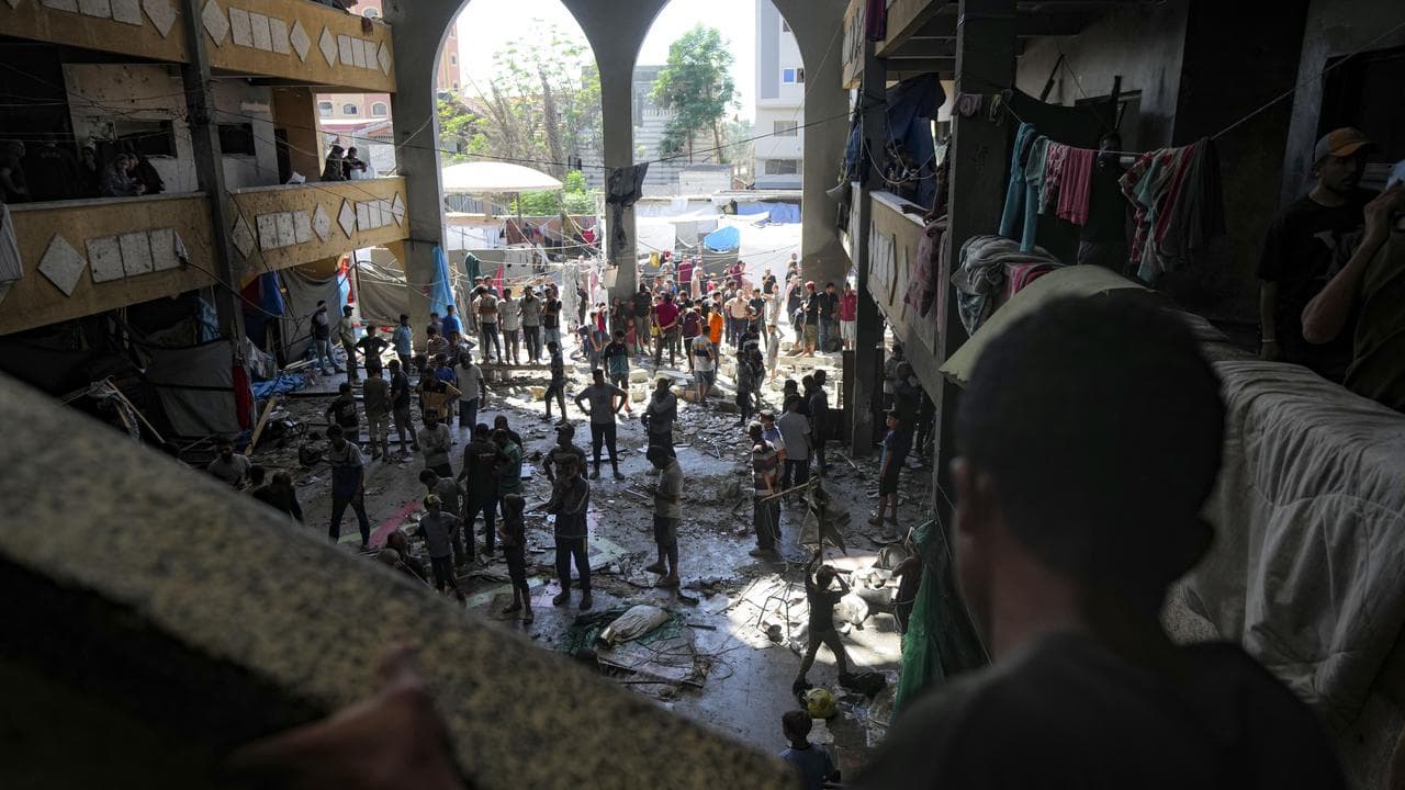 Palestinians inspect the damage of a school hit by a bomb
