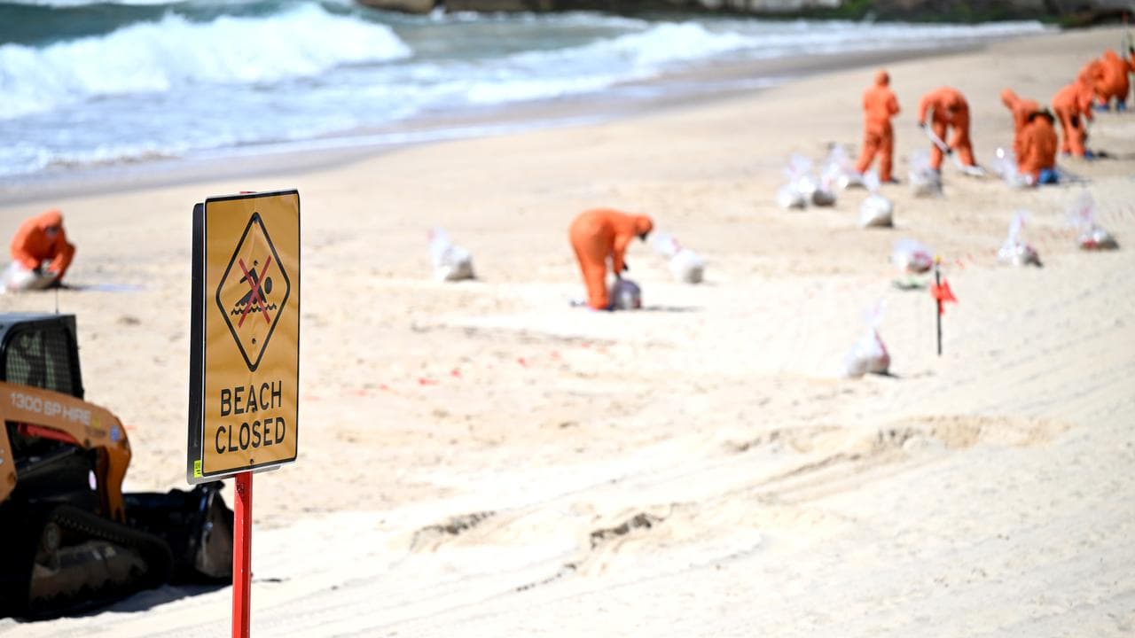 Workers clean up unkown debris washed up on Coogee Beach, Sydney