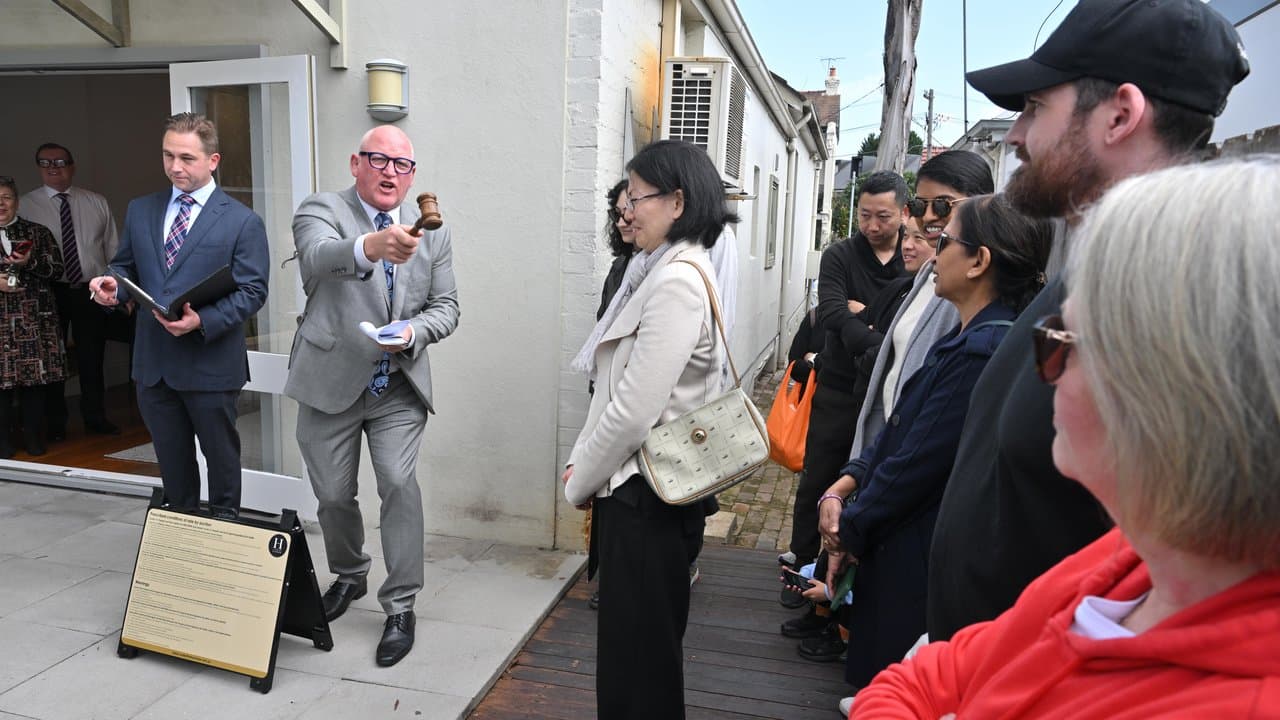 An auctioneer congratulates the winning buyers of a house