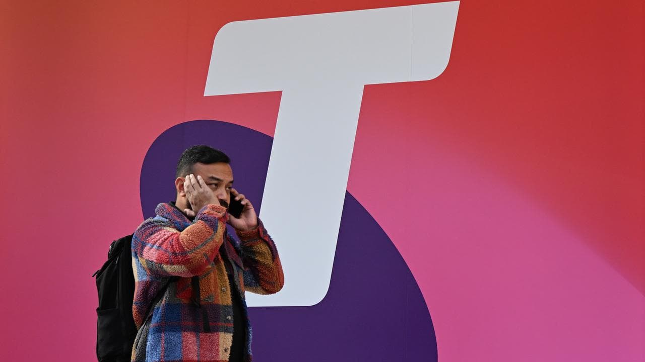 A man using a mobile walks past Telstra signage (file image)