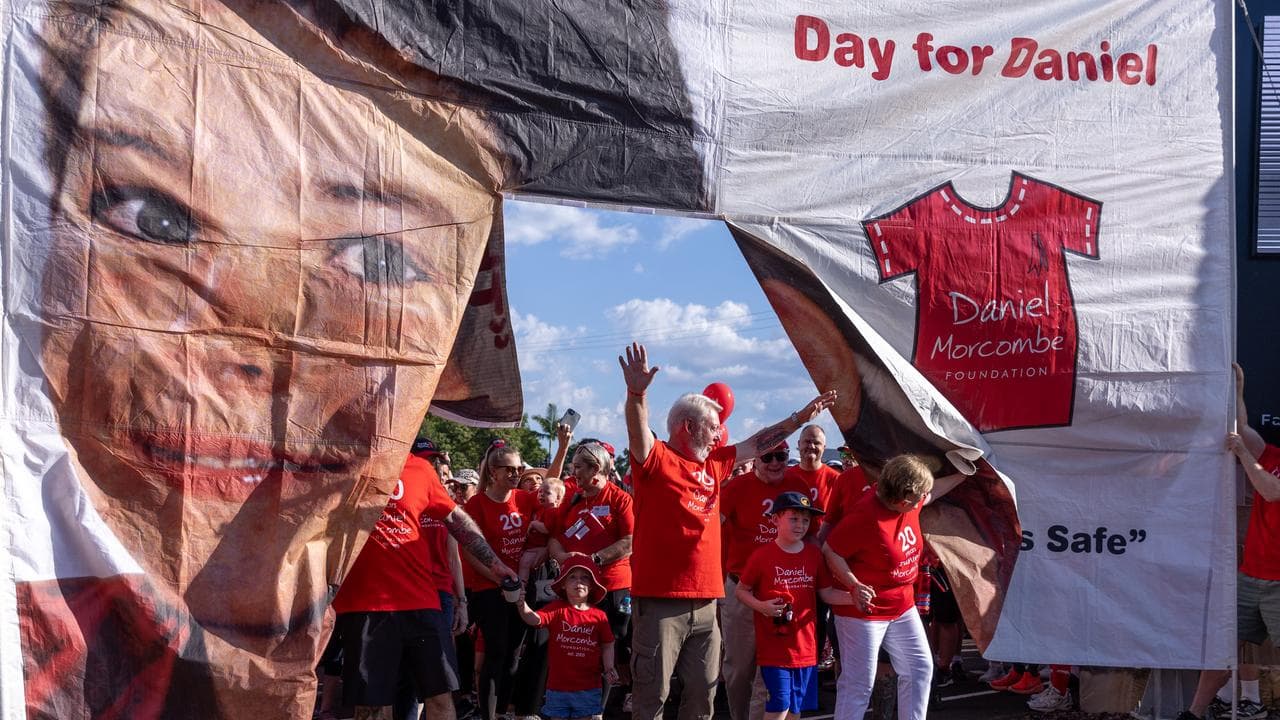 Morcombe family walk through a banner at the Walk for Daniel in 2024