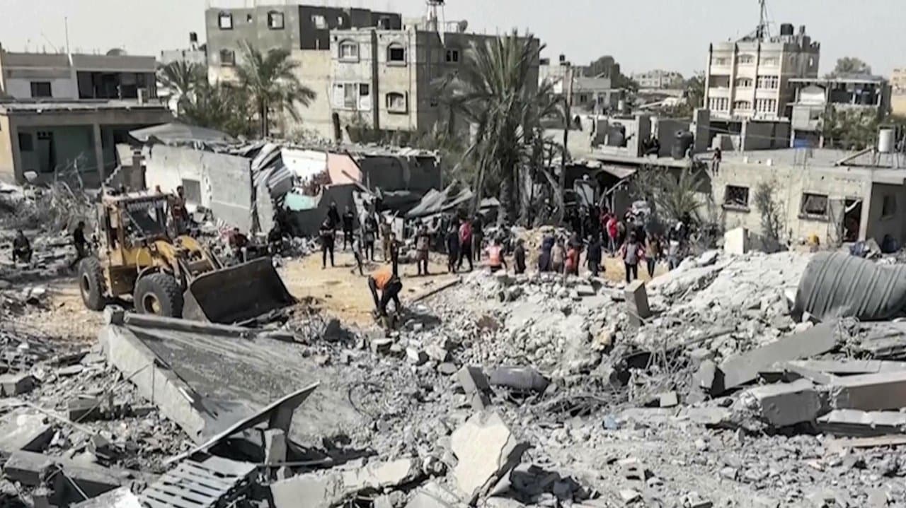 Palestinians gather near a building destroyed by Israeli air strikes