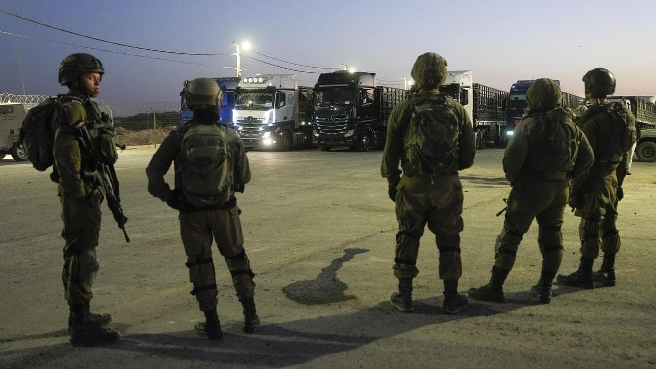 Israeli soldiers stand near trucks carrying humanitarian aid