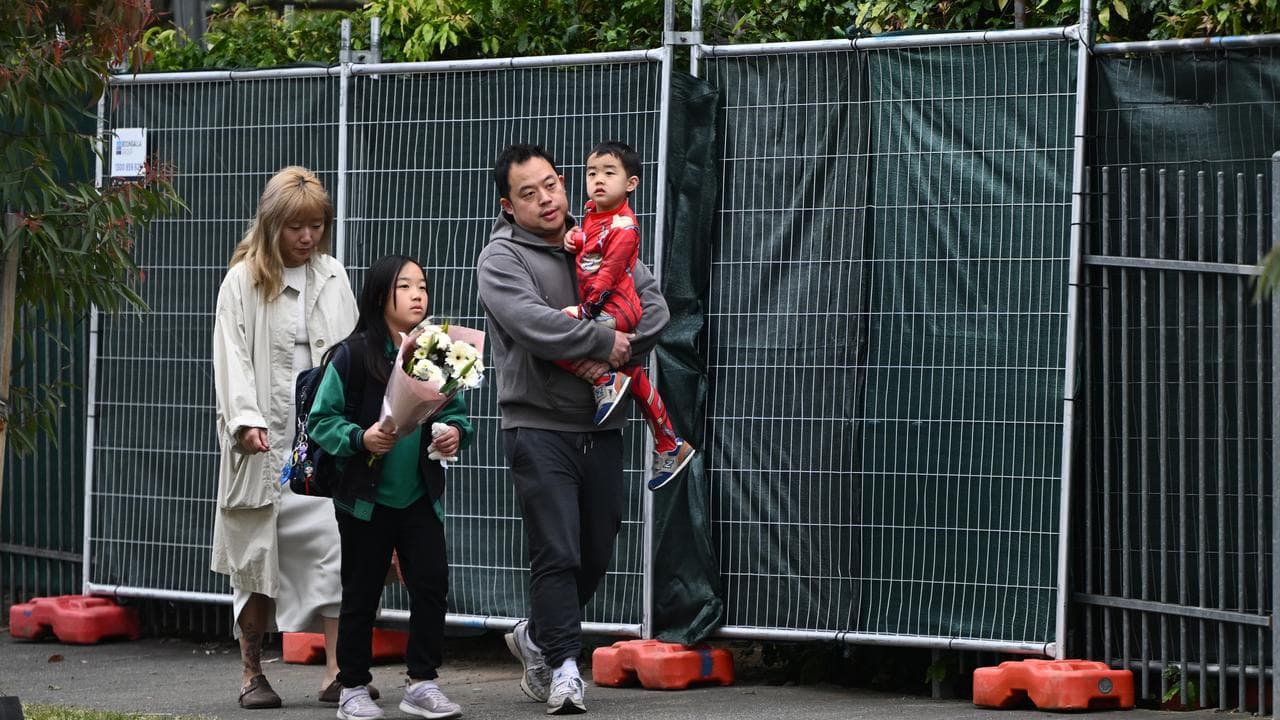 A student with a floral tribute at the site